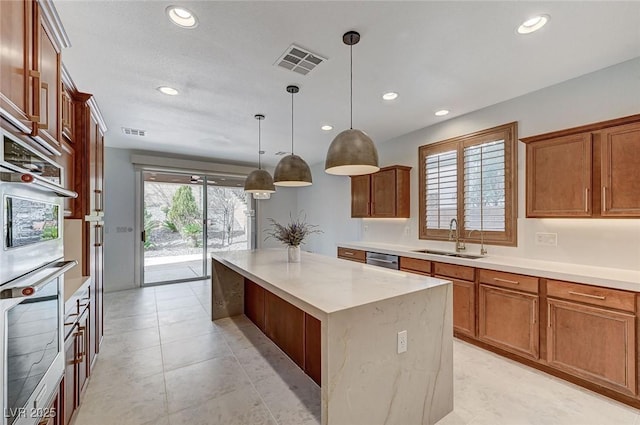 kitchen featuring sink, a center island, dishwasher, pendant lighting, and light stone countertops