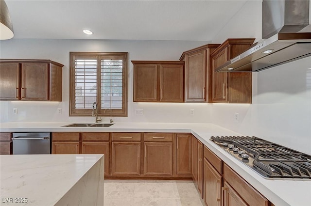 kitchen with wall chimney range hood, appliances with stainless steel finishes, light countertops, and a sink