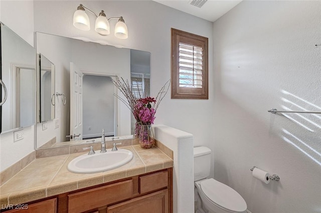 bathroom with visible vents, vanity, and toilet