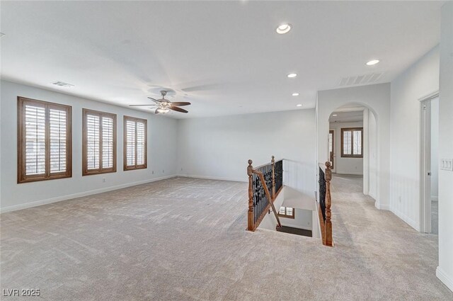 carpeted spare room featuring a wealth of natural light and ceiling fan