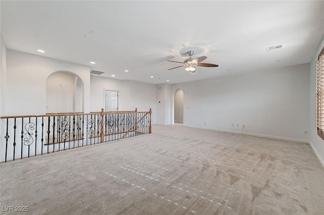 unfurnished room with visible vents, arched walkways, carpet flooring, and recessed lighting