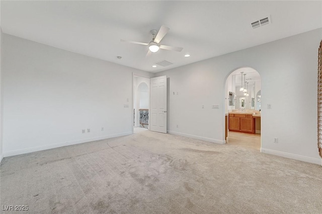 unfurnished bedroom featuring connected bathroom, light colored carpet, and ceiling fan