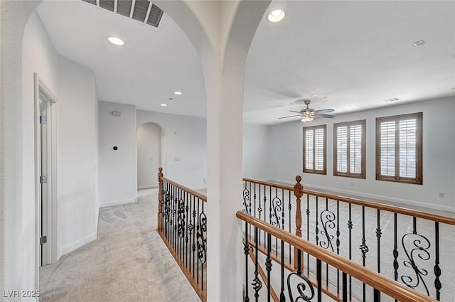 hall featuring visible vents, arched walkways, baseboards, light colored carpet, and recessed lighting