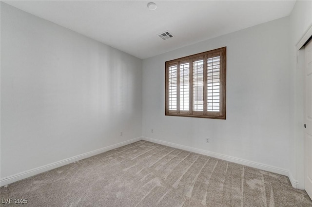 carpeted spare room with visible vents and baseboards