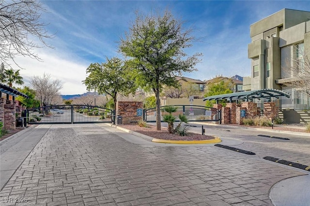 view of street with a gate, a gated entry, a mountain view, and curbs