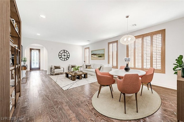 dining space with plenty of natural light, visible vents, arched walkways, and wood finished floors