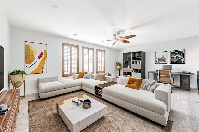 living area featuring baseboards, visible vents, and ceiling fan