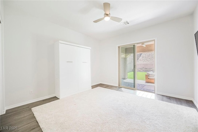 unfurnished room featuring a ceiling fan, visible vents, baseboards, and dark wood-type flooring