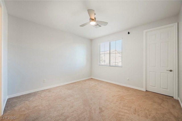 spare room with a ceiling fan, visible vents, light carpet, and baseboards