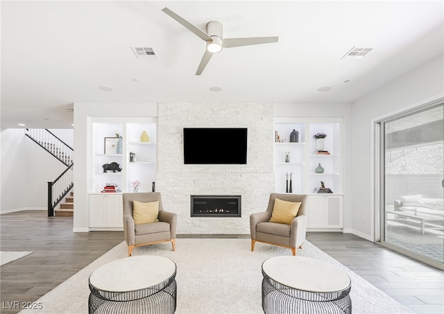 living area with built in shelves, visible vents, and stairway