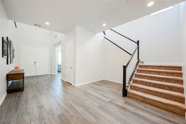 foyer entrance featuring light wood-type flooring, visible vents, recessed lighting, and stairs