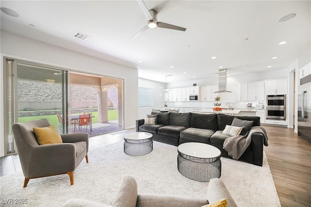 living area featuring light wood finished floors, visible vents, baseboards, ceiling fan, and recessed lighting