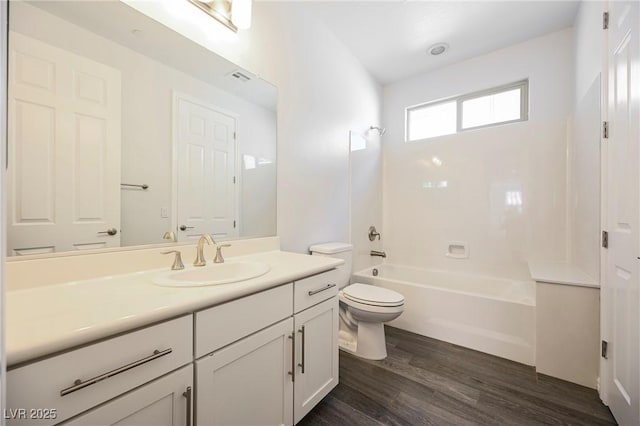 full bathroom featuring visible vents, toilet, wood finished floors, vanity, and washtub / shower combination