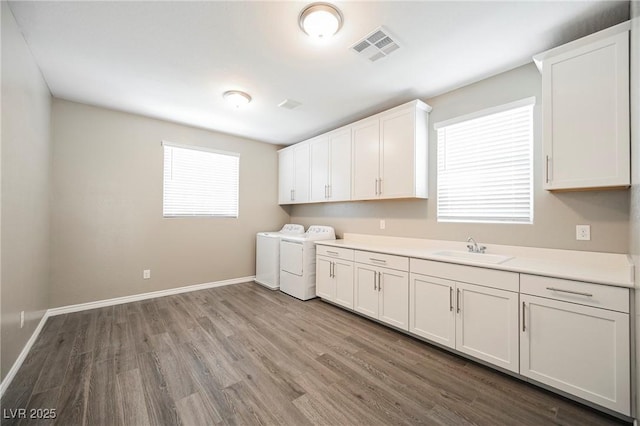 clothes washing area featuring a sink, visible vents, baseboards, independent washer and dryer, and cabinet space