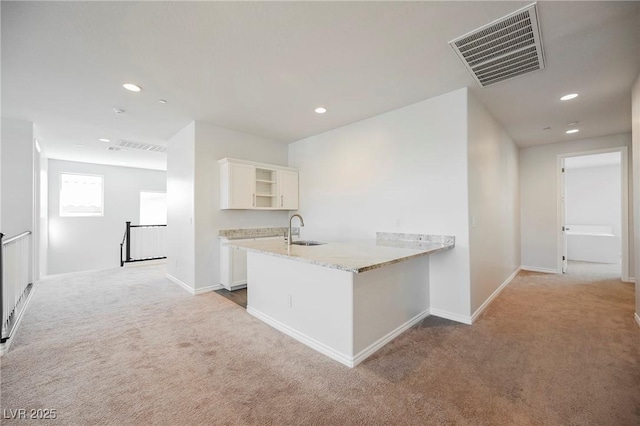 kitchen featuring light carpet, a peninsula, visible vents, white cabinets, and open shelves