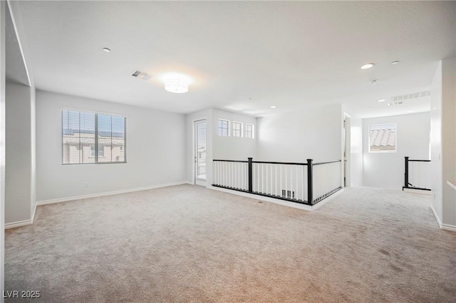 unfurnished room with a healthy amount of sunlight, visible vents, and light carpet