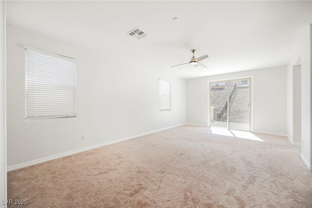 spare room featuring baseboards, visible vents, ceiling fan, and light colored carpet