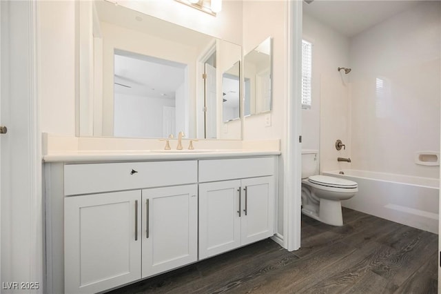 full bath featuring shower / bath combination, toilet, wood finished floors, and vanity