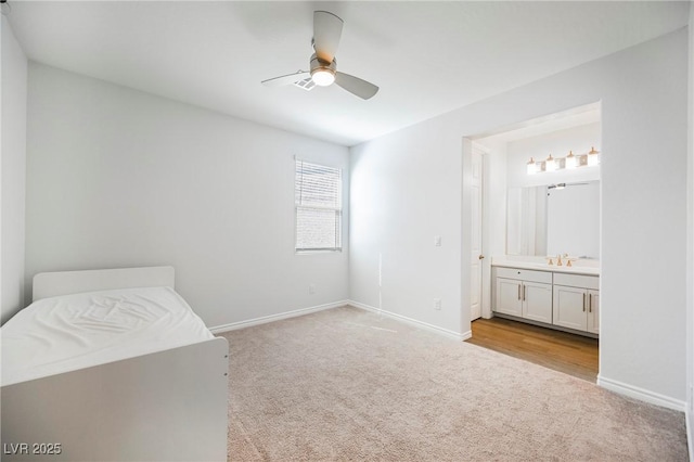 unfurnished bedroom with light carpet, baseboards, a ceiling fan, ensuite bath, and a sink