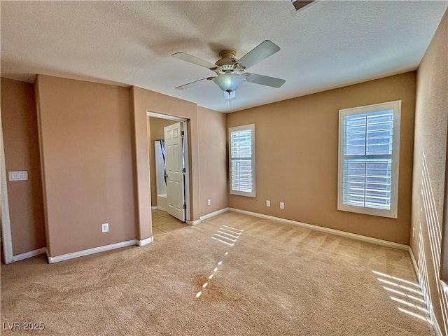 unfurnished bedroom featuring ceiling fan, light colored carpet, connected bathroom, and a textured ceiling