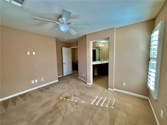 unfurnished bedroom with ceiling fan, light carpet, and ensuite bath