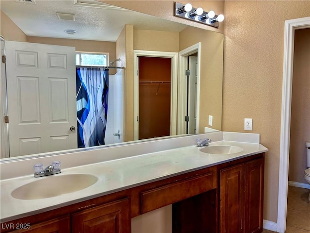 bathroom featuring walk in shower, vanity, toilet, and a textured ceiling