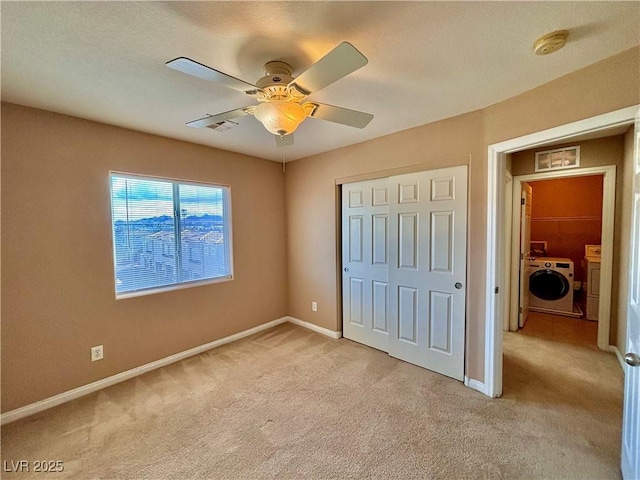 unfurnished bedroom with ceiling fan, independent washer and dryer, a closet, and light carpet