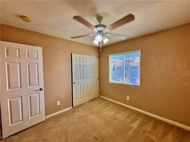 unfurnished bedroom featuring light carpet, ceiling fan, and a closet