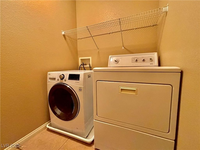 clothes washing area with washing machine and clothes dryer and tile patterned floors