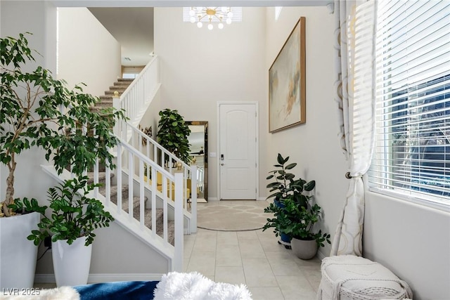 tiled entrance foyer featuring a notable chandelier and a high ceiling