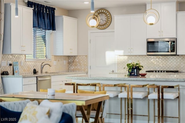 kitchen with appliances with stainless steel finishes, a breakfast bar area, hanging light fixtures, and white cabinets