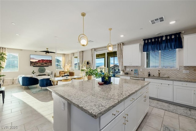 kitchen with sink, a kitchen island, white cabinets, pendant lighting, and backsplash