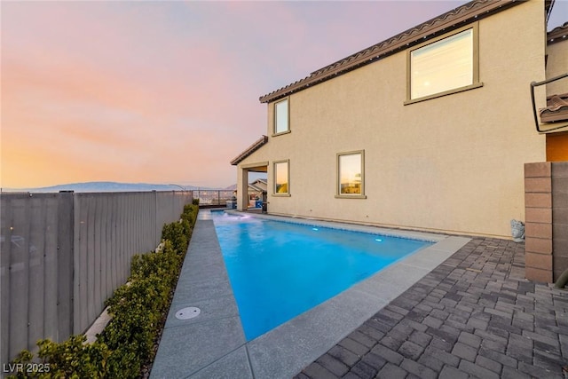 pool at dusk with a patio area