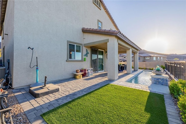 rear view of property with a fenced in pool, a patio, and a lawn