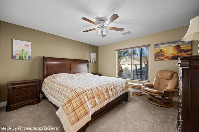 carpeted bedroom with ceiling fan and a textured ceiling