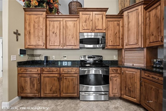 kitchen with appliances with stainless steel finishes and dark stone counters