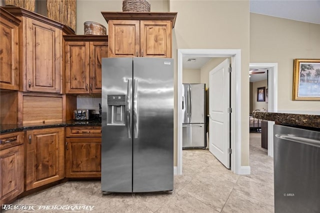 kitchen featuring stainless steel appliances, lofted ceiling, and dark stone countertops