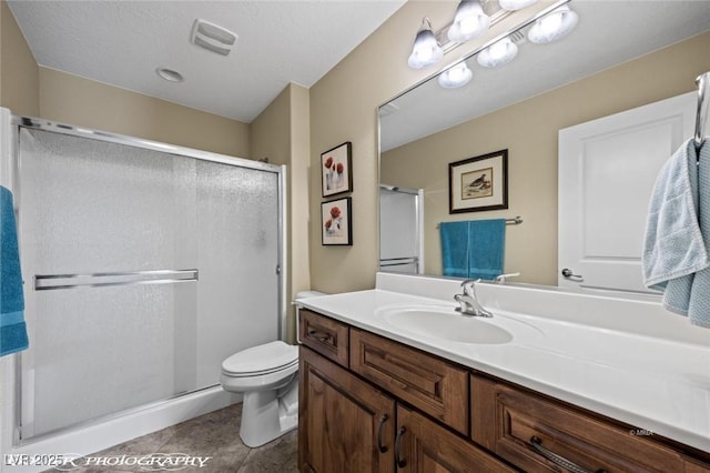 bathroom with vanity, a shower with shower door, tile patterned floors, and toilet