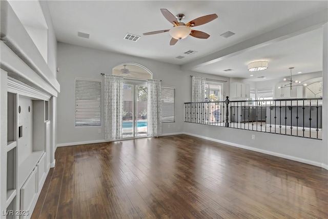 unfurnished living room featuring dark wood-style floors, visible vents, baseboards, and a ceiling fan