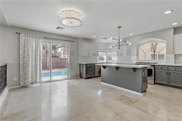 kitchen featuring stainless steel appliances, light countertops, visible vents, decorative backsplash, and a kitchen breakfast bar