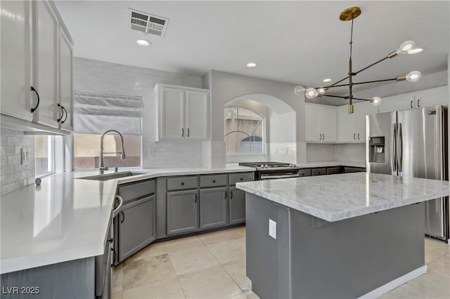 kitchen with gray cabinets, visible vents, backsplash, appliances with stainless steel finishes, and a sink