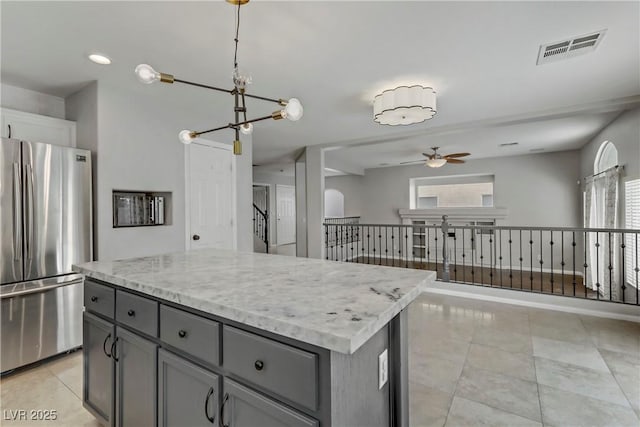 kitchen featuring freestanding refrigerator, gray cabinets, visible vents, and a healthy amount of sunlight