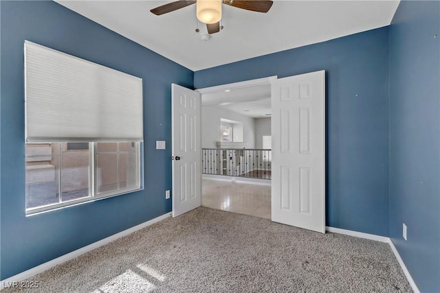 empty room with ceiling fan, carpet, and baseboards