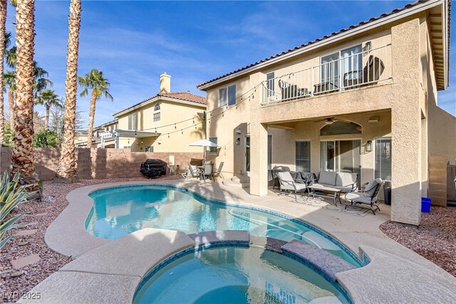 rear view of property featuring ceiling fan, a patio, an outdoor living space, a pool with hot tub, and a balcony