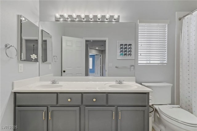 full bathroom with double vanity, toilet, and a sink