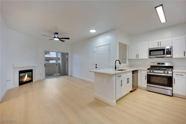 kitchen featuring stainless steel appliances, sink, white cabinets, and kitchen peninsula