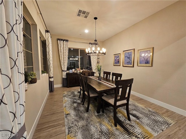 dining space with an inviting chandelier and dark hardwood / wood-style flooring