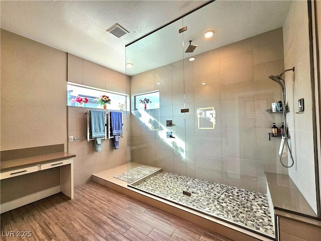 bathroom with a tile shower, hardwood / wood-style flooring, and a textured ceiling