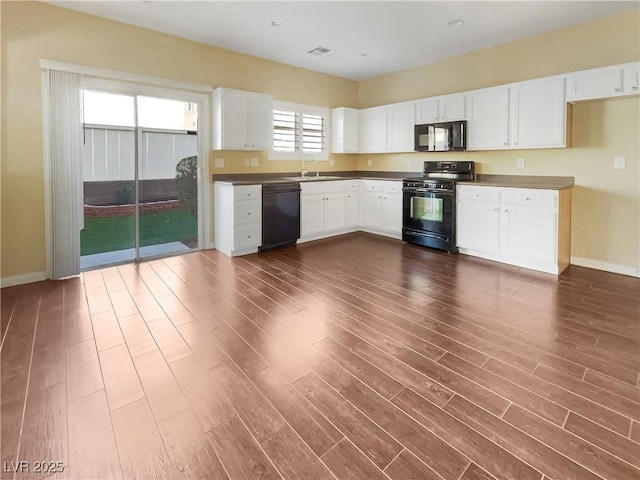 kitchen with dark hardwood / wood-style flooring, sink, black appliances, and white cabinets