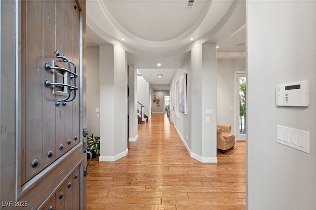 corridor featuring light wood-type flooring and a tray ceiling